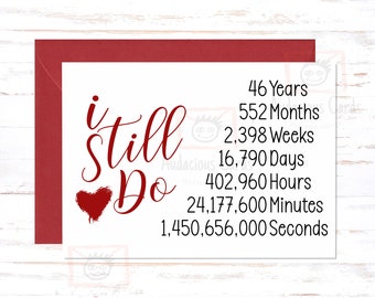 May include: A red and white card with the text "I Still Do" and a red heart. The card also includes a list of time measurements in years, months, weeks, days, hours, minutes, and seconds.