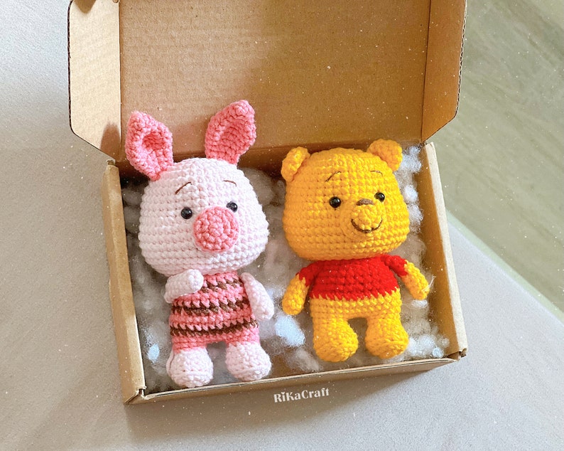 Pu&ograve; includere: Due giocattoli di peluche all'uncinetto in una scatola di cartone. Il primo giocattolo &egrave; un maiale rosa con strisce marroni e rosa. Il secondo giocattolo &egrave; un orso giallo con una camicia rossa.