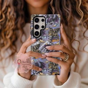 Puede incluir: Una funda de teléfono con un diseño de dragón de fantasía. La funda presenta un patrón repetido de dragones, espadas, libros y rayos sobre un fondo morado claro. El texto "FOURTH WINGS" es visible en un libro. La funda es sostenida por una persona.