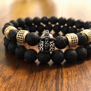 May include: Two black lava rock beaded bracelets with gold spacers and a silver gladiator helmet charm.