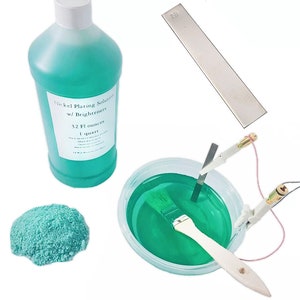 May include: A collection of nickel plating supplies, including a bottle of green liquid labeled "Nickel Plating Solution w/ Brighteners", a small pile of blue-green powder, a metal strip, and a container with a brush and green liquid.