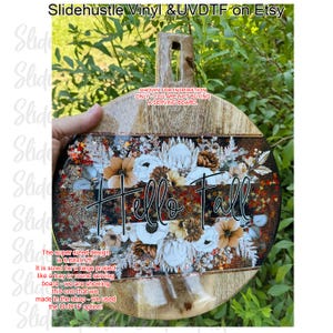 May include: A wooden serving board with a handle, featuring a floral design and the words "Hello Fall." The design includes white, brown, and orange flowers, with glitter accents. The board measures 6.60 x 9.25 inches.