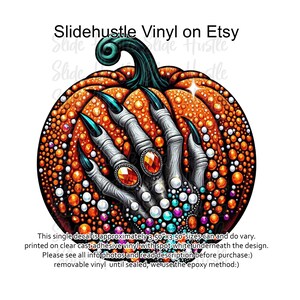 May include: A 3.50" x 3.50" vinyl decal of a pumpkin with a hand reaching out from inside. The pumpkin is orange with white and turquoise dots. The hand is white with turquoise fingernails and has a large, red jewel ring on it.