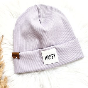 Könnte beinhalten: Eine gerippte Mütze in Lavendelfarbe mit einem weißen Patch, auf dem "HAPPY" steht.