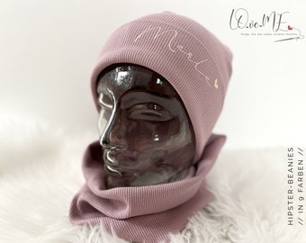 May include: A mauve ribbed beanie with a matching scarf. The beanie has the word "Me" embroidered on it in a gold thread.