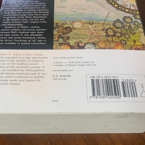 Pode incluir: Uma capa de livro com uma ilustra&ccedil;&atilde;o detalhada de uma f&ecirc;nix que emerge das chamas. O t&iacute;tulo do livro &eacute; "The Secret Teachings of All Ages" de Manly P. Hall. O design da capa &eacute; de Nita Ybarra. O livro &eacute; publicado por Jeremy P. Tarcher/Penguin.