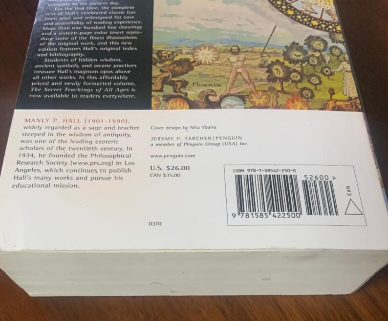 Pode incluir: Uma capa de livro com uma ilustra&ccedil;&atilde;o detalhada de uma f&ecirc;nix que emerge das chamas. O t&iacute;tulo do livro &eacute; "The Secret Teachings of All Ages" de Manly P. Hall. O design da capa &eacute; de Nita Ybarra. O livro &eacute; publicado por Jeremy P. Tarcher/Penguin.