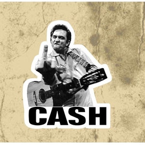 May include: Black and white photo of Johnny Cash holding a guitar and giving the middle finger. The word "CASH" is written in bold black letters below the image.