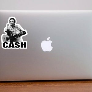May include: A black and white sticker of Johnny Cash playing a guitar with the word "CASH" in bold letters below him.