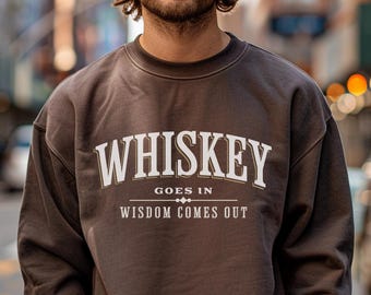 Può includere: Una felpa marrone con la scritta "Whiskey Goes In Wisdom Comes Out" stampata sul davanti.