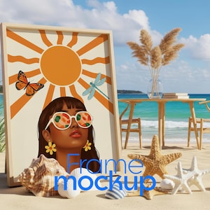May include: A framed art print featuring a woman wearing sunglasses with a colorful design, a sun, butterfly, and dragonfly. The artwork is displayed on a sandy beach with seashells and starfish. A table and chairs are in the background.