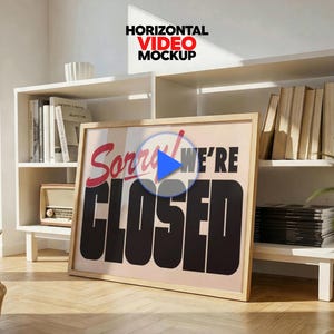 Peut inclure: Une affiche encadrée avec les mots "Sorry We're Closed" en rouge et noir. L'affiche est appuyée contre une étagère blanche avec des livres et une radio vintage. Un panier en osier et une plante en pot sont au premier plan.