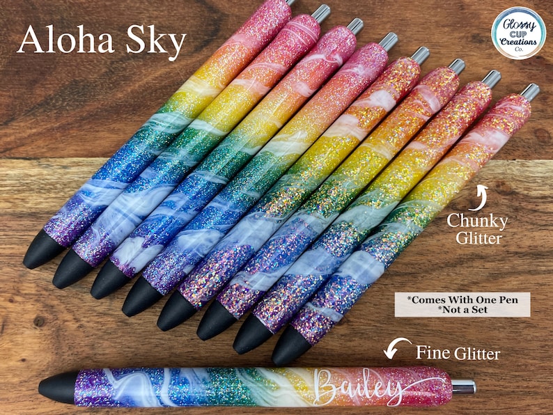 Puede incluir: Un conjunto de bol&iacute;grafos de purpurina arco&iacute;ris con un dise&ntilde;o de remolino blanco. Los bol&iacute;grafos tienen una opci&oacute;n de purpurina gruesa y purpurina fina. El texto "Aloha Sky" y "Glossy Cup Creations Co." es visible en la imagen. El texto "Chunky Glitter", "Fine Glitter" y "*Comes With One Pen *Not a Set" tambi&eacute;n es visible en la imagen.