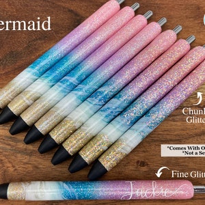 Puede incluir: Un conjunto de diez bol&iacute;grafos con tem&aacute;tica de sirena con un degradado de purpurina rosa, azul y blanca. Los bol&iacute;grafos tienen un acabado de purpurina gruesa y un acabado de purpurina fina. El texto "Mermaid" y "Glossy Cup Creations Co." es visible en la imagen. El texto "Chunky Glitter", "Fine Glitter" y "*Comes With One Pen *Not a Set" tambi&eacute;n es visible en la imagen.
