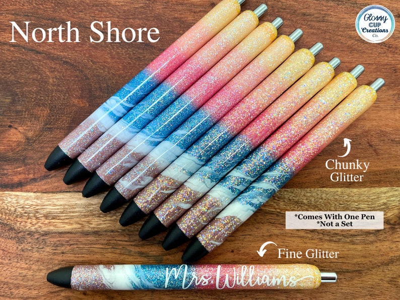 Puede incluir: Un conjunto de diez bol&iacute;grafos con purpurina y un dise&ntilde;o marmoleado. Los bol&iacute;grafos tienen un degradado de purpurina rosa, azul y blanca. Los bol&iacute;grafos est&aacute;n etiquetados como "North Shore" y "Mrs. Williams".