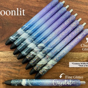 Puede incluir: Un conjunto de ocho bol&iacute;grafos con un degradado de purpurina azul y morada. Los bol&iacute;grafos tienen un dise&ntilde;o de m&aacute;rmol blanco y est&aacute;n etiquetados como "Moonlit" y "Crystal". El texto "Chunky Glitter" y "Fine Glitter" tambi&eacute;n es visible en la imagen. El texto "*Comes With One Pen *Not a Set" tambi&eacute;n es visible en la imagen.