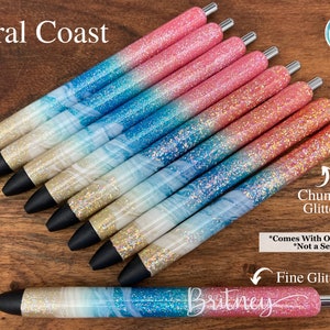 Puede incluir: Un conjunto de diez bol&iacute;grafos con purpurina con un degradado de colores rosa y azul. Los bol&iacute;grafos tienen un dise&ntilde;o de m&aacute;rmol blanco con purpurina dorada. Los bol&iacute;grafos est&aacute;n etiquetados como "Coral Coast" y "Chunky Glitter".