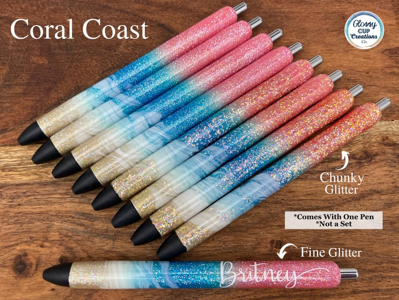 Puede incluir: Un conjunto de diez bol&iacute;grafos con purpurina con un degradado de colores rosa y azul. Los bol&iacute;grafos tienen un dise&ntilde;o de m&aacute;rmol blanco con purpurina dorada. Los bol&iacute;grafos est&aacute;n etiquetados como "Coral Coast" y "Chunky Glitter".