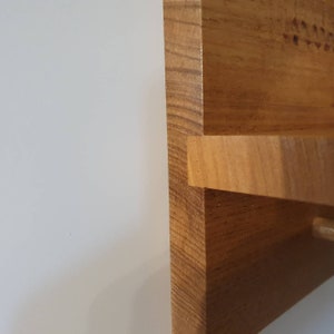 K&ouml;nnte beinhalten: Nahaufnahme einer Ecke eines Holzregals. Das Regal ist aus Naturholz mit einer hellbraunen Oberfl&auml;che. Das Regal ist abgewinkelt und leicht gebogen.