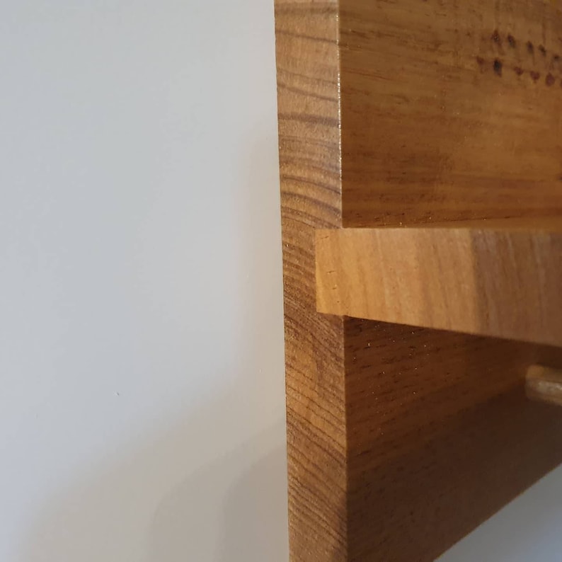 K&ouml;nnte beinhalten: Nahaufnahme einer Ecke eines Holzregals. Das Regal ist aus Naturholz mit einer hellbraunen Oberfl&auml;che. Das Regal ist abgewinkelt und leicht gebogen.