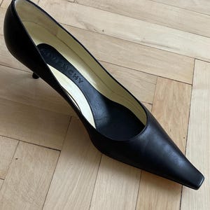 K&ouml;nnte beinhalten: Schwarze Lederpumps mit spitzer Zehenkappe und niedrigem Absatz. Die Schuhe haben ein schlichtes Design und sind aus hochwertigem Leder gefertigt. Der Markenname "Givenchy" ist auf der Innensohle sichtbar.