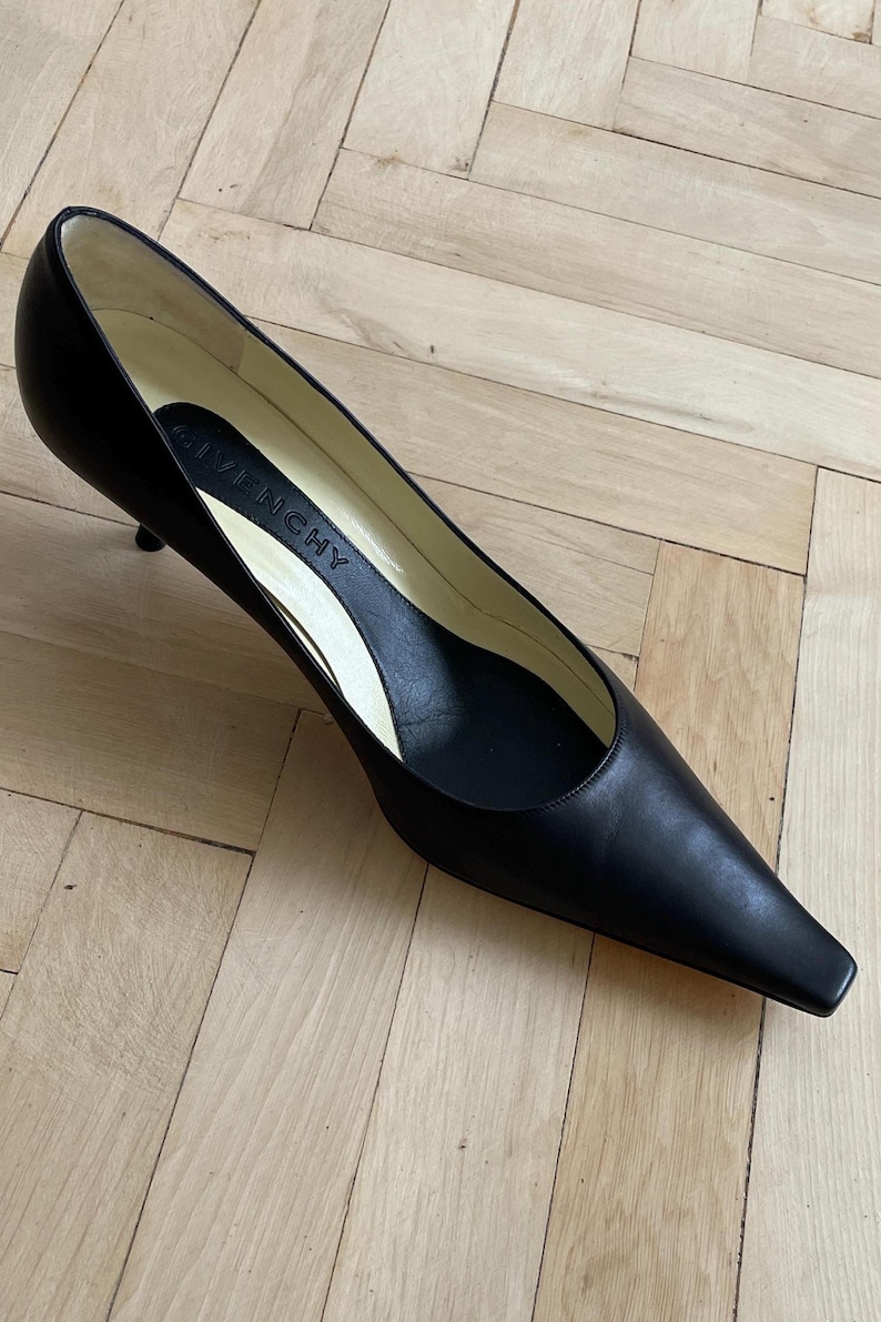 K&ouml;nnte beinhalten: Schwarze Lederpumps mit spitzer Zehenkappe und niedrigem Absatz. Die Schuhe haben ein schlichtes Design und sind aus hochwertigem Leder gefertigt. Der Markenname "Givenchy" ist auf der Innensohle sichtbar.