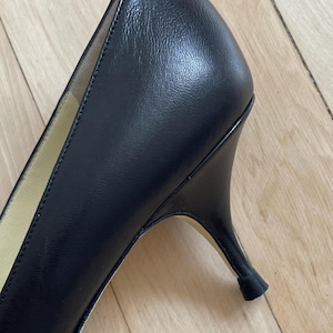 K&ouml;nnte beinhalten: Schwarzer Lederschuh mit Absatz, spitzem Zeh und niedrigem Absatz.