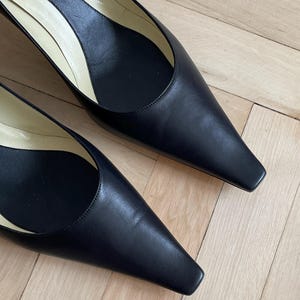 K&ouml;nnte beinhalten: Ein Paar schwarze, spitze Pumps aus Leder mit niedrigem Absatz. Die Schuhe haben ein schlichtes Design und sind aus hochwertigem Leder gefertigt. Der Markenname "Givenchy" ist auf der Innensohle eines Schuhs sichtbar.
