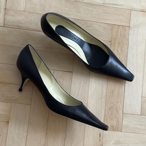 K&ouml;nnte beinhalten: Ein Paar schwarze, spitze Pumps aus Leder mit einem Stiletto-Absatz. Die Schuhe haben ein schlichtes Design und sind aus hochwertigem Leder gefertigt. Der Markenname "Givenchy" ist auf der Innensohle eines Schuhs sichtbar.