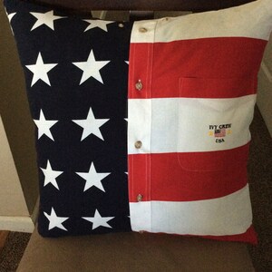 May include: A red, white, and blue pillow with a button-down shirt design. The pillow has a pocket with the text "IVY CREW USA" embroidered on it.