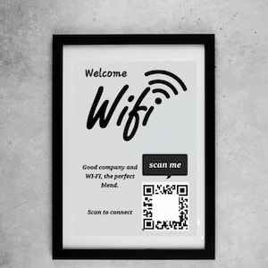 May include: A framed print with a black border. The print has the word "Welcome" above the word "Wifi" in a stylized font. Below, it reads "Good company and WI-FI, the perfect blend." A QR code and the words "scan me" are also present.