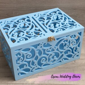 May include: A light blue wooden box with a decorative cut-out design. The box has a hinged lid with a gold latch. The box is perfect for storing small items or as a decorative piece.