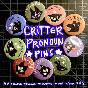 May include: A collection of colorful round pins with various critter illustrations and pronoun labels. The pins feature text like "He/They," "She/Her," and "They/Them." The text "Critter Pronoun Pins" is also displayed.