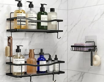 May include: Black metal shower shelves with various bath products, including shampoo, body wash, and toner bottles. A soap dish with a bar of soap and a loofah are also visible. The shelves are mounted on a white marble tile wall.
