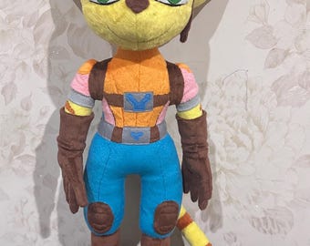May include: A plush toy of a yellow and orange cat-like character with brown boots, blue pants, and a brown vest. The character has a yellow tail with orange stripes.