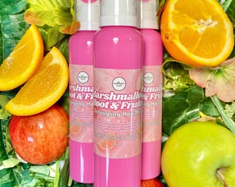 May include: Three pink spray bottles of Marshmallow Root & Fruit Detangling Hair Mist, each containing 207 ml. The labels feature white text and a circular logo. The bottles are surrounded by fresh green leaves, orange slices, and red and green apples.