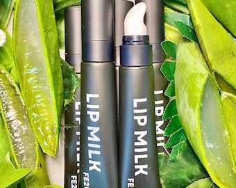 May include: Black tubes of Lip Milk lip product with white text, surrounded by green aloe vera leaves. The product has a black cap and a white applicator. The text "FE2U" is printed below the product name.