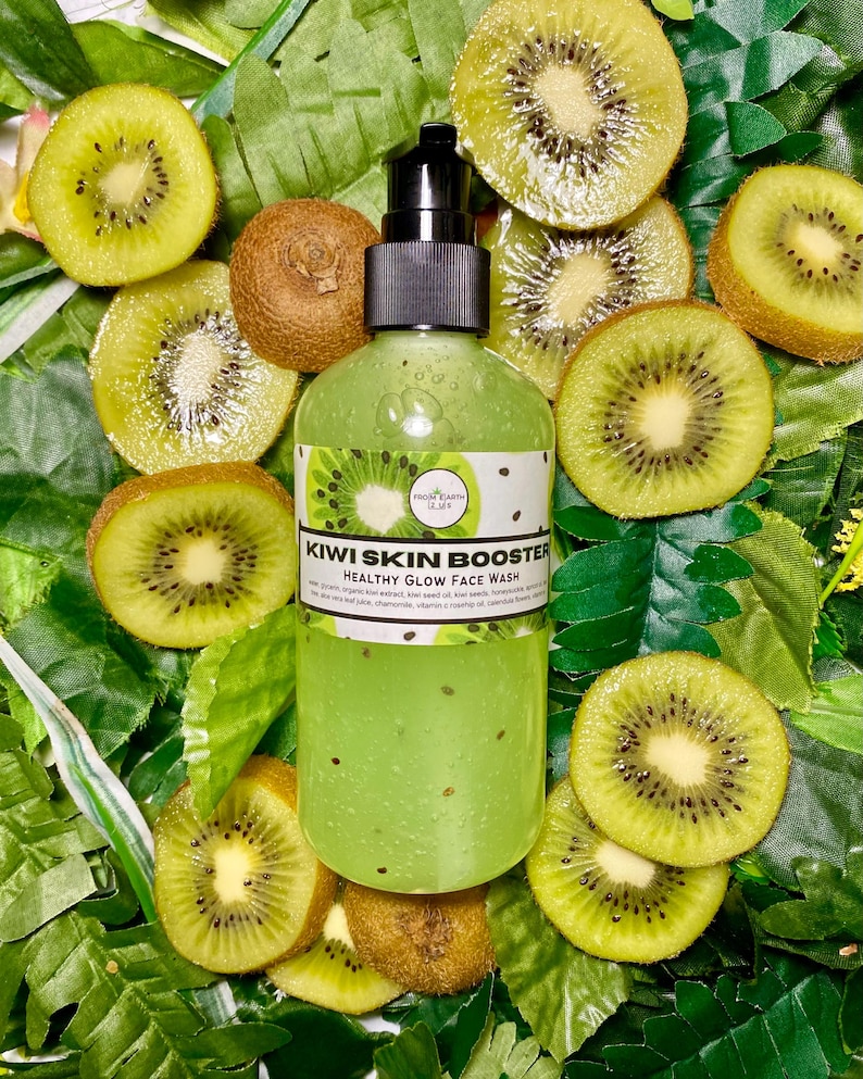 May include: A clear green bottle of kiwi skin booster healthy glow face wash with a black pump top. The bottle is surrounded by kiwi fruit slices on a green leafy background.