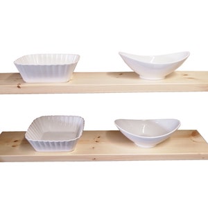 Puede incluir: Dos estantes de madera con cuatro cuencos de cerámica blanca. Los estantes son de madera natural de color marrón claro. Los cuencos son de diferentes formas y tamaños.