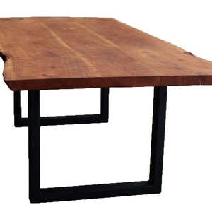 May include: A long, wooden table with a live edge top and black metal legs. The table is made of natural wood with a rich brown color.