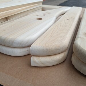 K&ouml;nnte beinhalten: Nahaufnahme von zwei unfertigen Holzst&uuml;cken mit abgerundeten Kanten. Das Holz ist hellbraun und hat eine glatte Oberfl&auml;che.