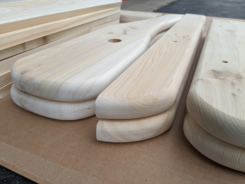 K&ouml;nnte beinhalten: Nahaufnahme von zwei unfertigen Holzst&uuml;cken mit abgerundeten Kanten. Das Holz ist hellbraun und hat eine glatte Oberfl&auml;che.