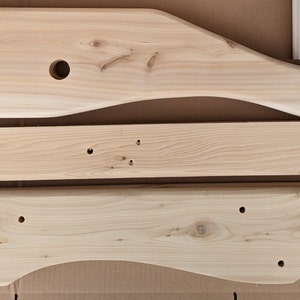 K&ouml;nnte beinhalten: Drei unfertige Holzst&uuml;cke f&uuml;r ein M&ouml;belprojekt. Die St&uuml;cke sind alle in verschiedenen Formen und Gr&ouml;&szlig;en und haben L&ouml;cher, die zum Zusammenbauen gebohrt wurden.