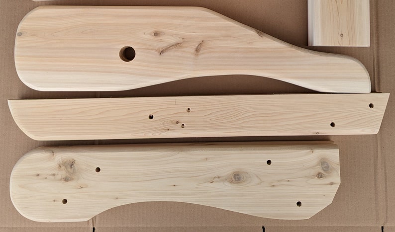 K&ouml;nnte beinhalten: Drei unfertige Holzst&uuml;cke f&uuml;r ein M&ouml;belprojekt. Die St&uuml;cke sind alle in verschiedenen Formen und Gr&ouml;&szlig;en und haben L&ouml;cher, die zum Zusammenbauen gebohrt wurden.