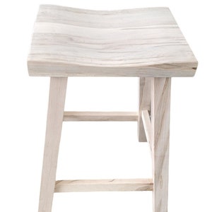 May include: A white wooden stool with a curved top and a simple, sturdy design. The stool has four legs and a crossbar for added support.