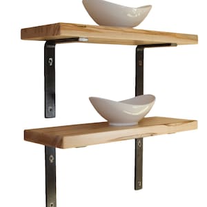 May include: Two wooden shelves with black metal brackets. The shelves are empty except for two white ceramic bowls.