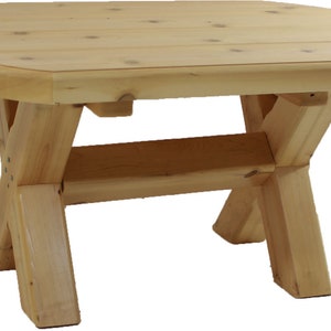 May include: A light-coloured wooden octagonal coffee table. The table has an X-shaped leg design and is made of unfinished wood. The table is approximately 76 cm long and 51 cm wide.