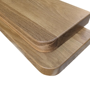 Könnte beinhalten: Zwei Holzregale mit abgerundeten Kanten. Die Regale sind aus hellbraunem Holz mit natürlicher Maserung.