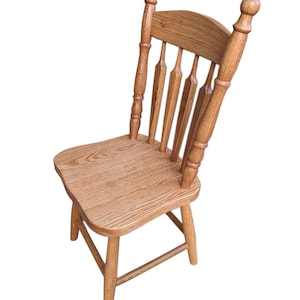 May include: A wooden chair with a spindle back and turned legs. The chair is made of light brown wood and has a natural finish.