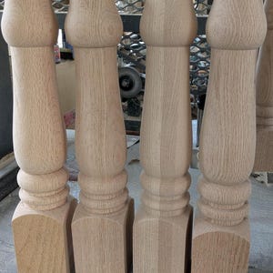 Peut inclure: Quatre pieds de table en bois non finis. Chaque pied a une base carrée, une section centrale tournée et un sommet bulbeux. Le grain du bois est visible et les pieds sont prêts à être finis. Ces pieds sont probablement pour une table à manger ou un meuble similaire.